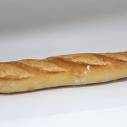 A baguette resting on a white surface, showcasing its long shape and crusty exterior