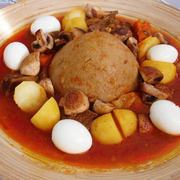 A plate of Bazin (center) served with a stew and whole hard-boiled eggs