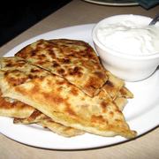 A plate of Afghan Bolani accompanied by a serving of sour cream