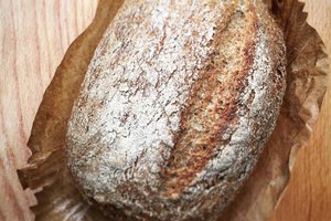 A loaf of bread resting on a rustic wooden table, showcasing its golden crust and inviting texture