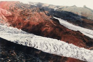 A glacier descending near Hof, with water cascading over the rugged mountain landscape